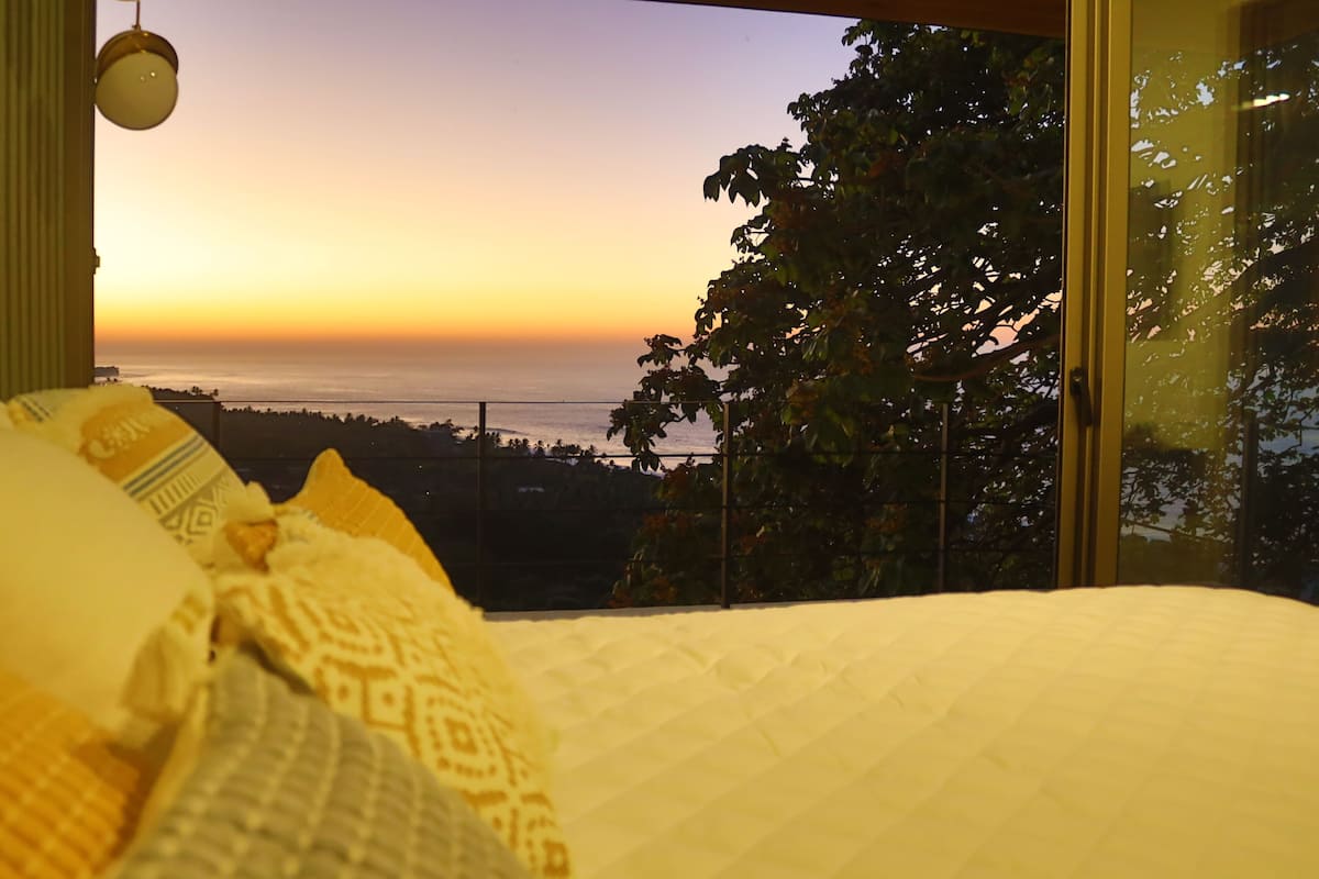 Une chambre avec une grande fenêtre donnant sur un magnifique coucher de soleil.