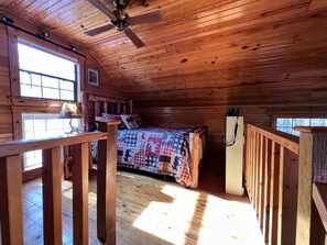 A wooden cabin bedroom with a bed, a ceiling fan, and a window. - Mountain View Creekside Cabin on 12 Acres. (Mountain View)