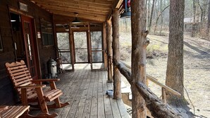 Una terraza de madera con mecedoras y un interior de cabaña rústica.