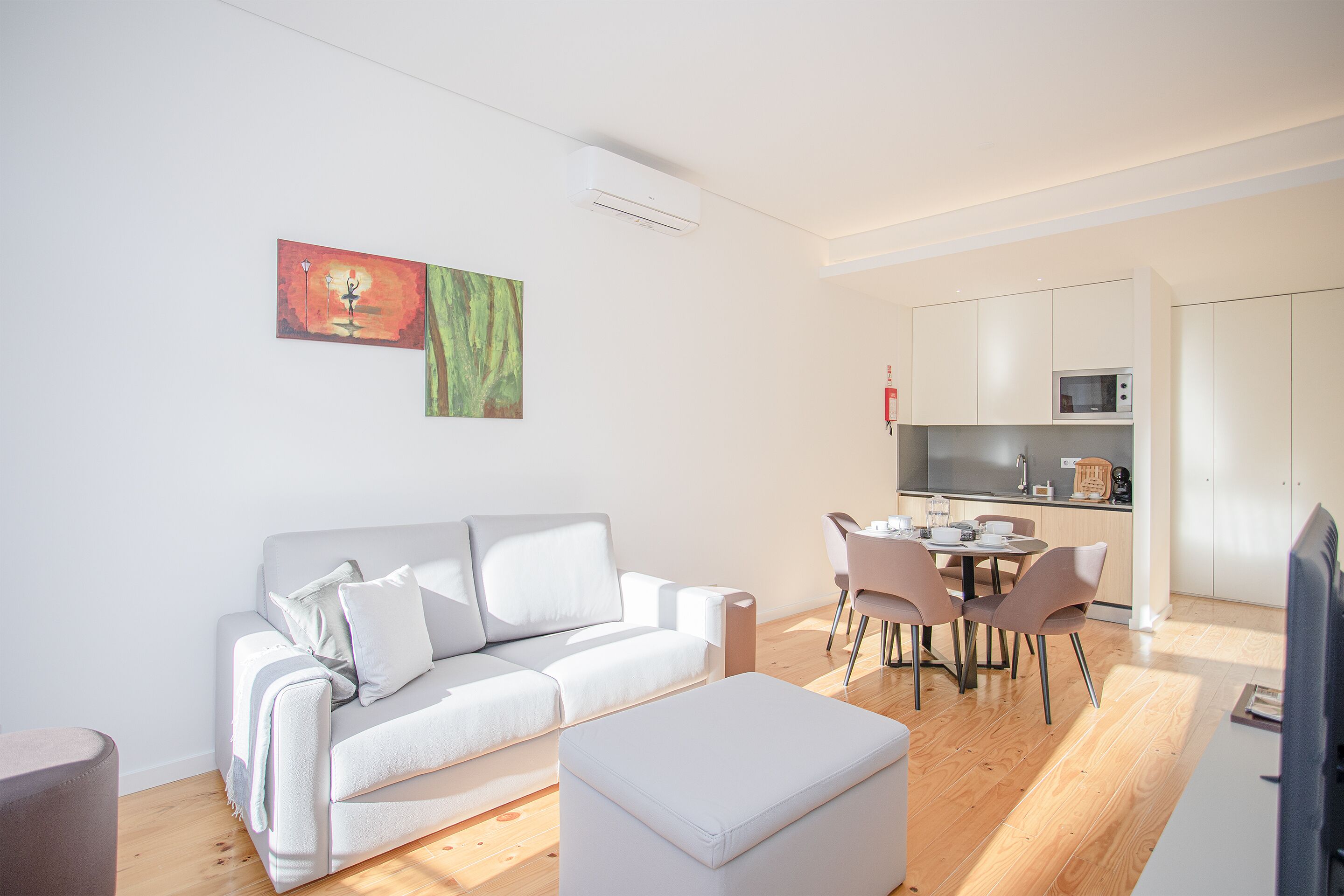 Ein modernes Wohnzimmer mit einer Couch, einem Hocker und einem Essbereich mit Stühlen und einem Tisch.