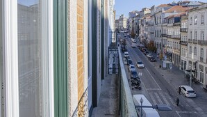 Un balcon donnant sur une rue de la ville, avec vue sur les immeubles et les voitures garées.