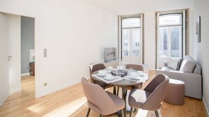 Un espace repas moderne avec une table ronde, six chaises et un canapé en arrière-plan.