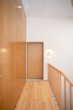 A wooden staircase with a handrail leading to a door. - Liiiving-Mouzinho Residence Apartment 3T (Porto)