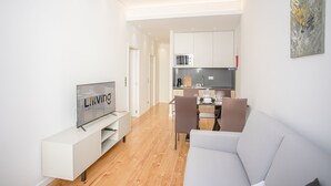 Un salon moderne doté d’un téléviseur à écran plat, d’un canapé et d’un coin repas avec des chaises et une table.