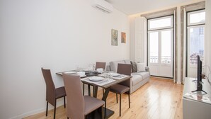 Un coin repas avec une table dressée pour quatre personnes, un canapé et un meuble pour la télévision.