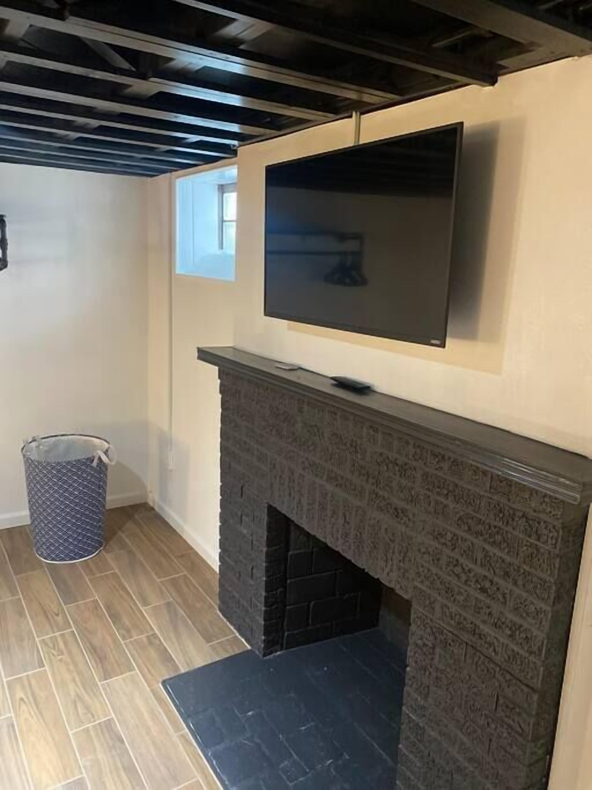 A room with a fireplace, a television mounted above it, and a window to the left.