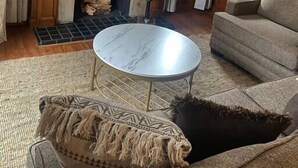 Un salon avec une cheminée, un téléviseur fixé au-dessus, une table basse ronde et un canapé.