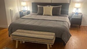 Une chambre à coucher avec un lit, des tables de chevet, un banc et une fenêtre.