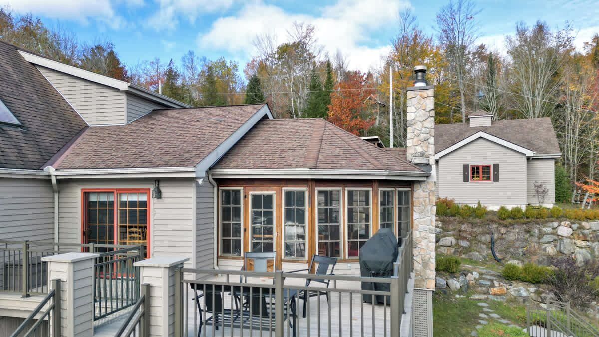 A house with a covered patio, a stone chimney, and a stone wall garden.