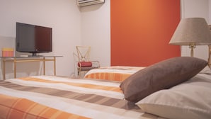 A hotel room with a bed, a TV, a chair, and a lamp. - Gaviotas Apartments (Mazatlán)