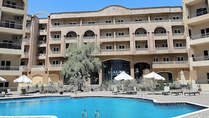 Un hotel con piscina, varios balcones y zonas de estar al aire libre.