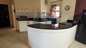 Una cocina con una isla central, microondas, hervidor y refrigerador.