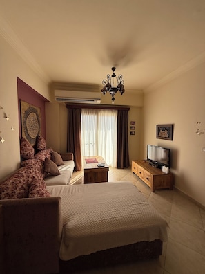 A hotel room with a bed, a sofa, a television, and a desk.