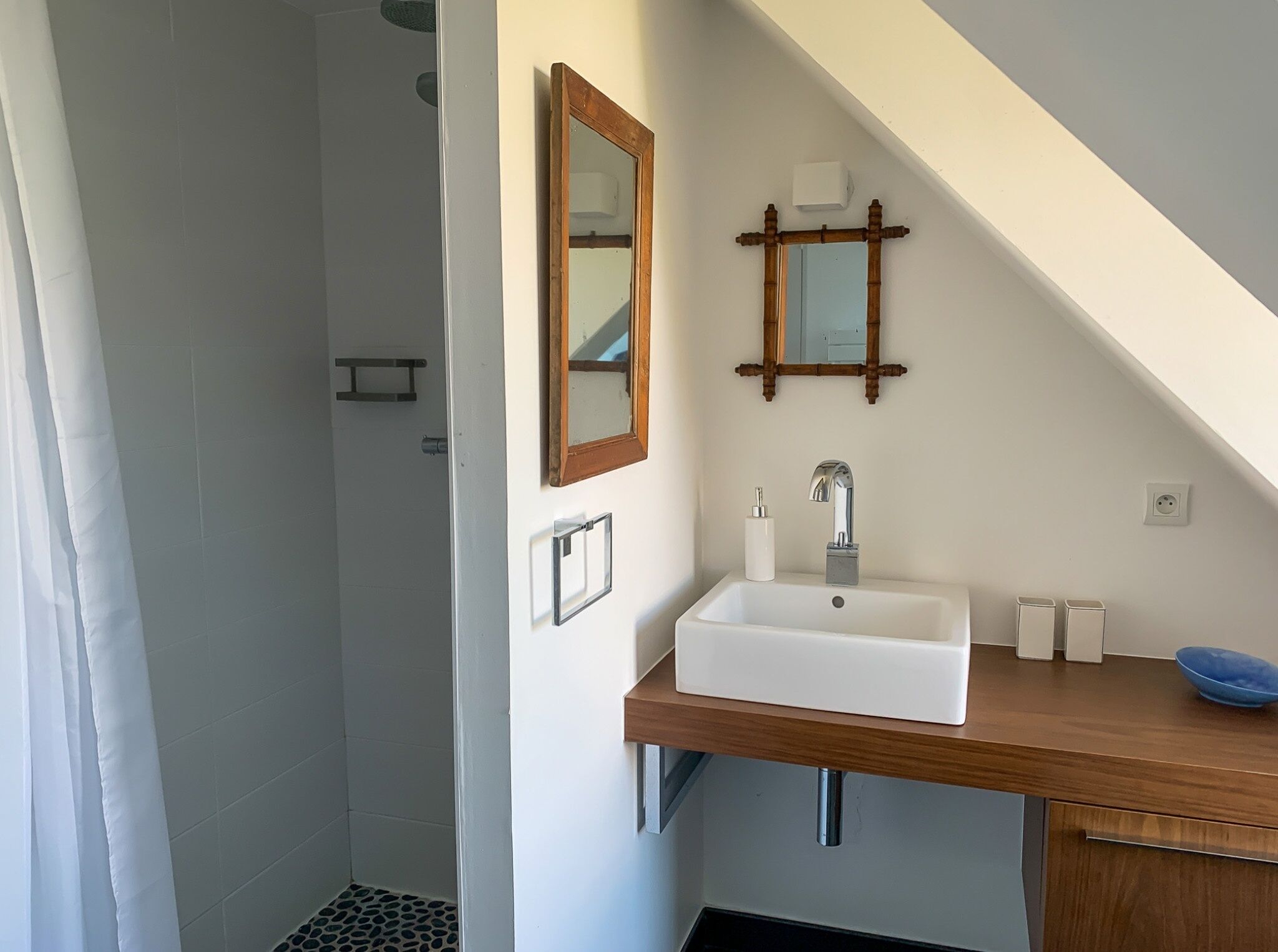 Ein Badezimmer mit einem weißen Waschbecken, einer Holzausziehtheke und einem Spiegel.