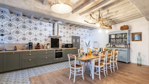 A modern kitchen with a central island, wooden dining table, and chairs. - Gite La Petite Ferme (Clermont-les-Fermes)