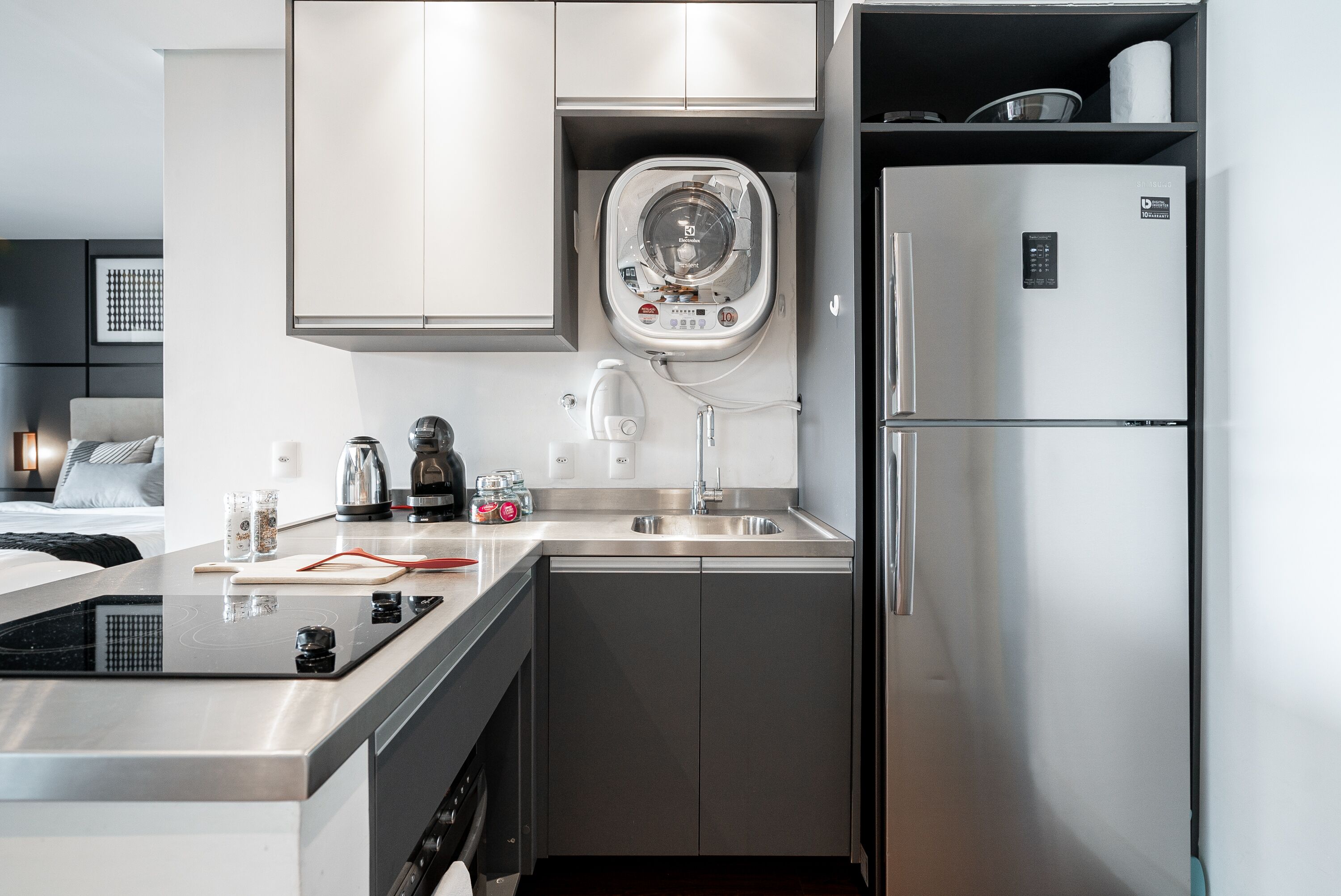 A modern kitchen with a built-in microwave, a stainless steel refrigerator, a sink, and a compact dishwasher.