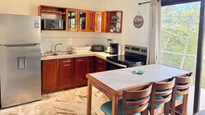 A modern kitchen with wooden cabinets, a stainless steel refrigerator, a microwave, a toaster, and a coffee maker. - Deluxe Penhouse with Pool - 3 min walk to the beach (Playa Pelada)