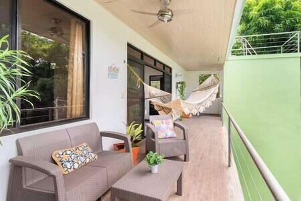 A balcony with a sofa, a small table, and a hammock.