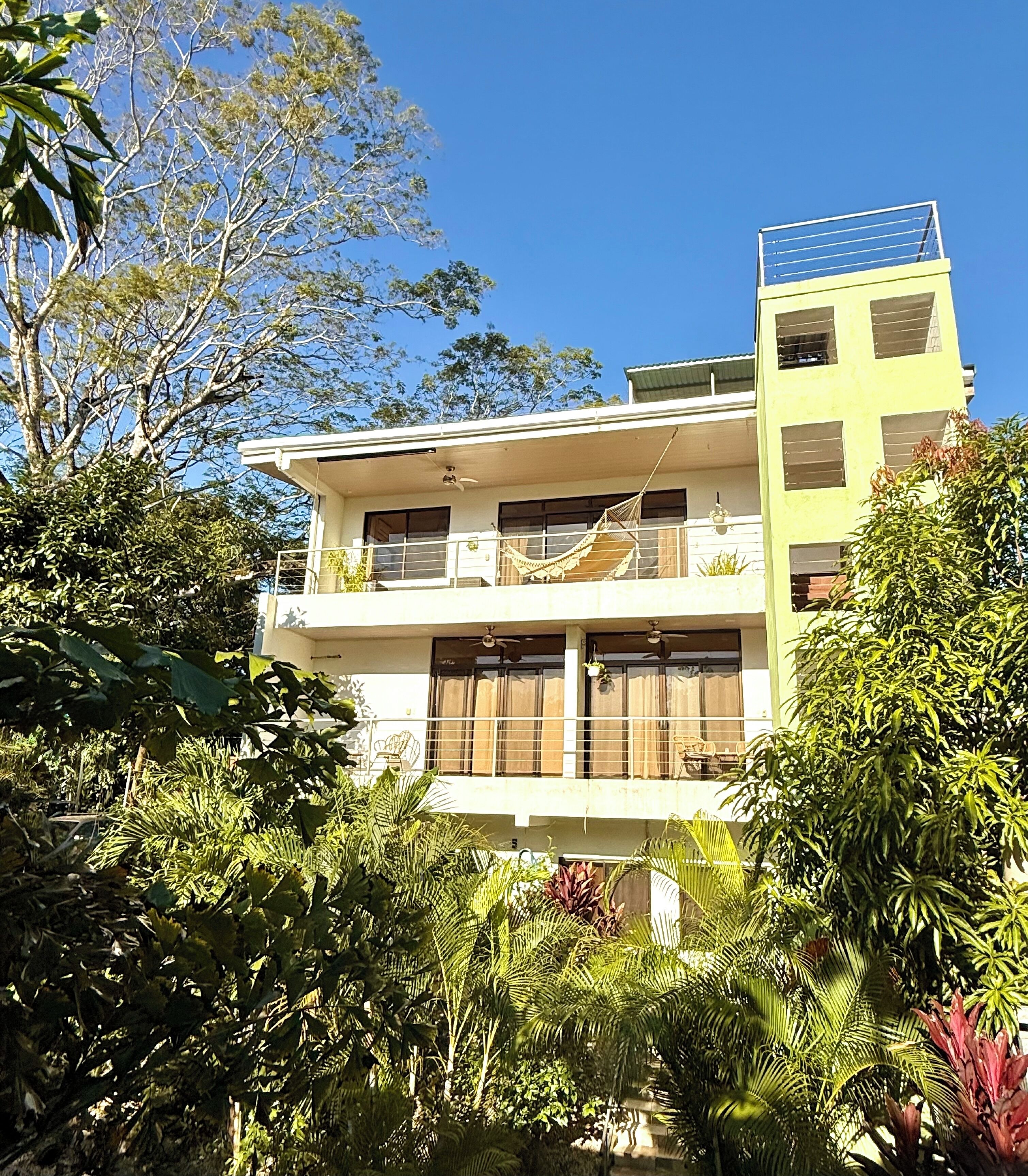 A two-story building with balconies, surrounded by dense tropical vegetation.
