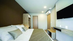 Una camera d'albergo moderna con un letto grande, una TV a parete e un armadio.