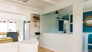 A bedroom with a bed, a white shelving unit, a mirror, and a view of a kitchen. - Steps from the water, Sandy beach - ahhh… (Brighton)