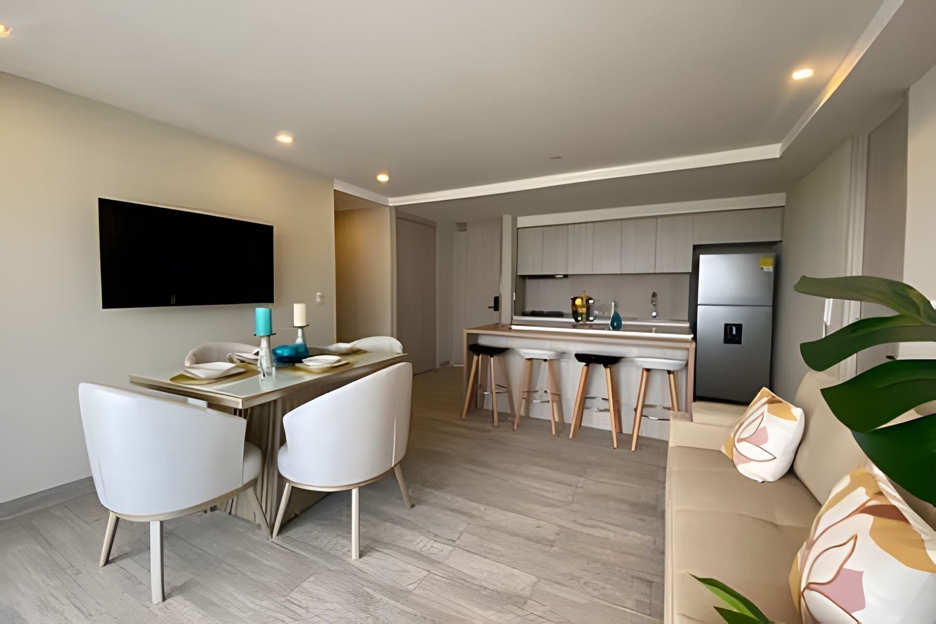 Eine moderne Küche mit Kühlschrank, ein Essbereich mit Tisch und Stühlen sowie ein Wohnbereich mit Sofa.
