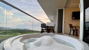 Un balcón con jacuzzi, zona de comedor y vista a la ciudad.