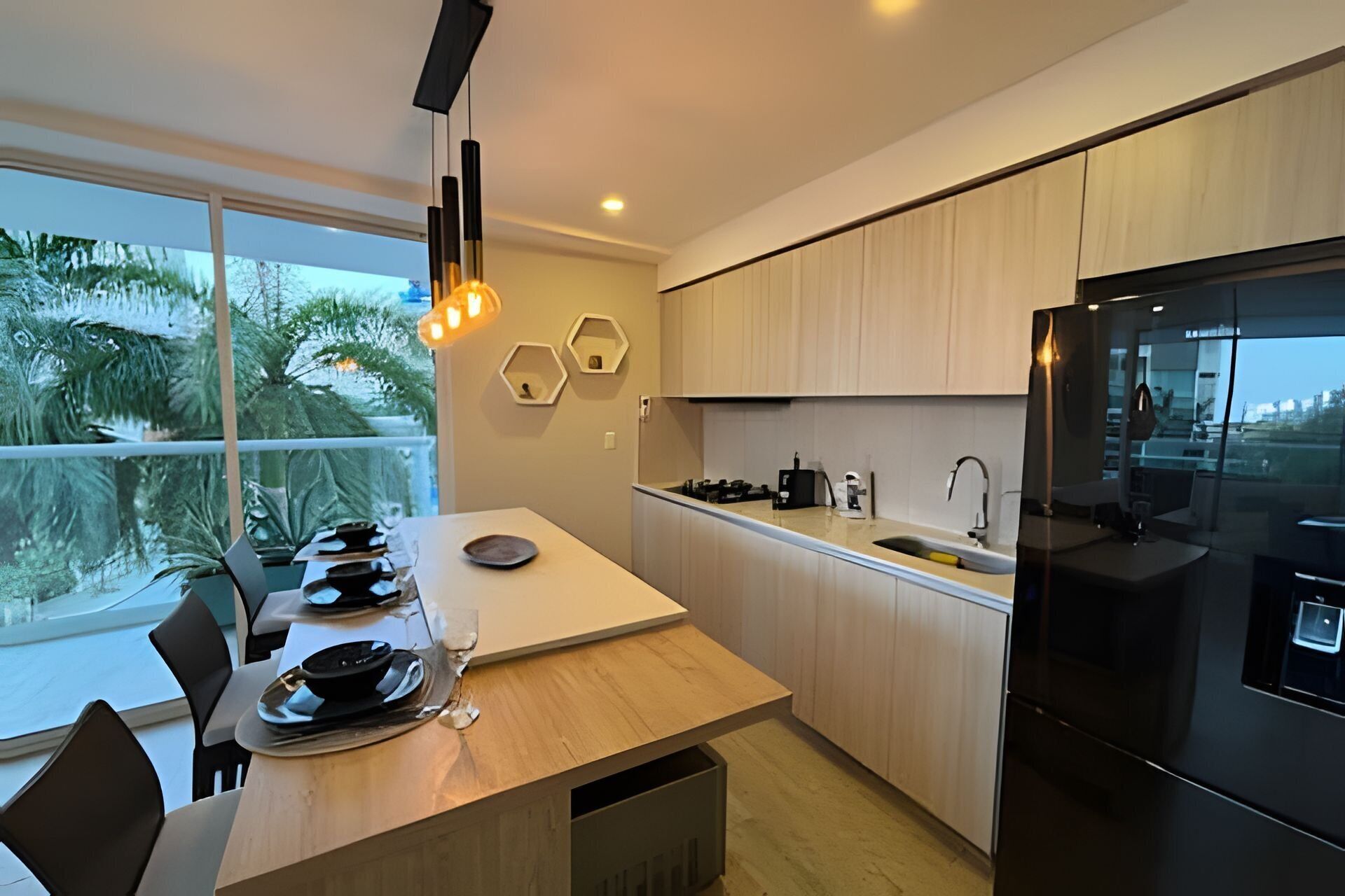 A modern kitchen with a large window, wooden cabinets, a black refrigerator, and a dining area with a table and chairs.