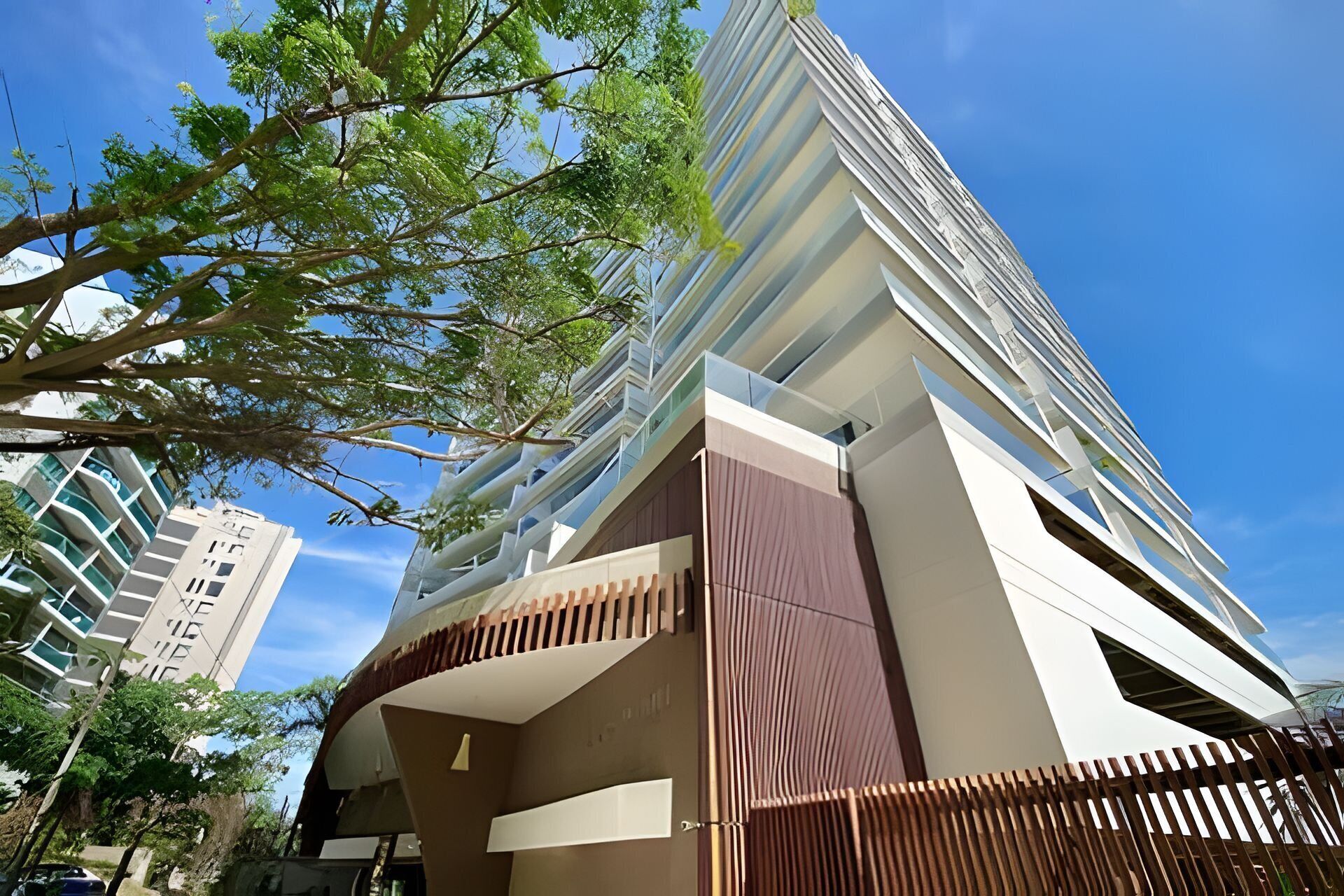A modern high-rise building with a curved facade, large windows, and a visible balcony area.