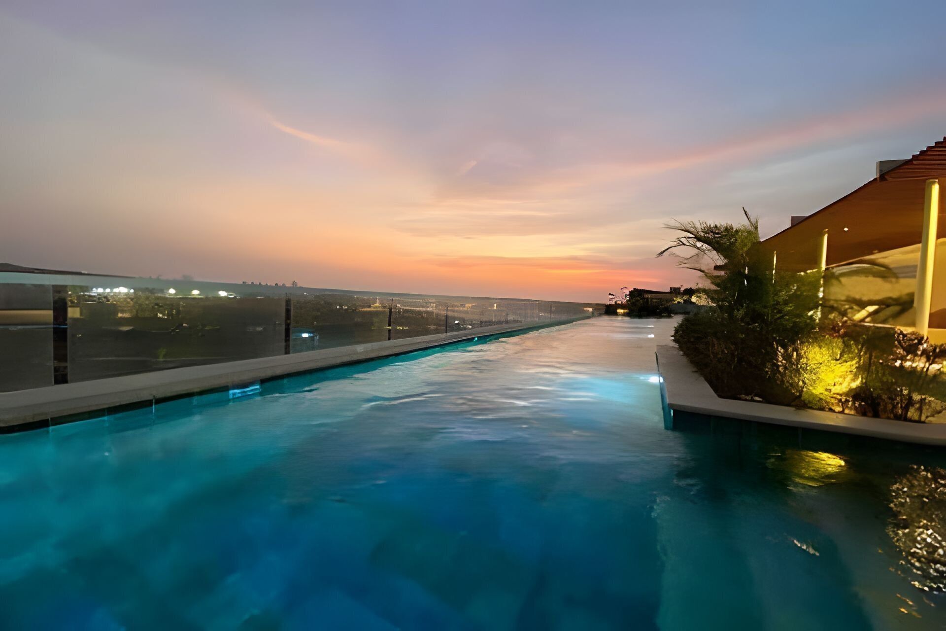 A swimming pool with a view of the cityscape at sunset.