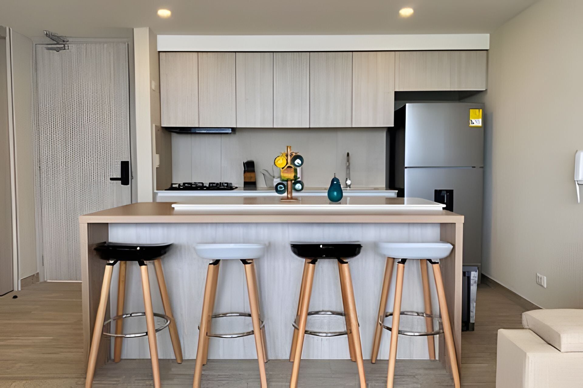 Une cuisine moderne dotée d’un îlot central, de tabourets de bar, d’un réfrigérateur et d’une cuisinière.