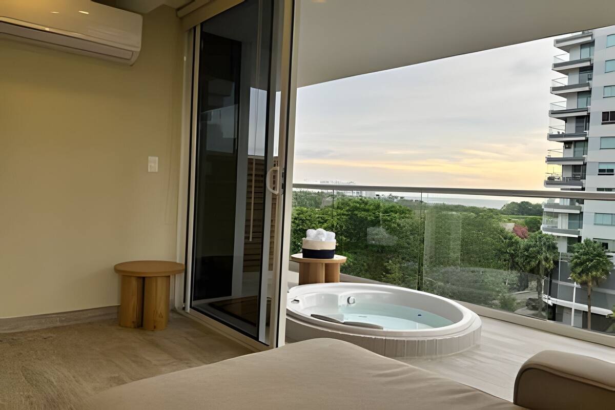 A balcony with a hot tub, a small round table, and a sliding glass door.