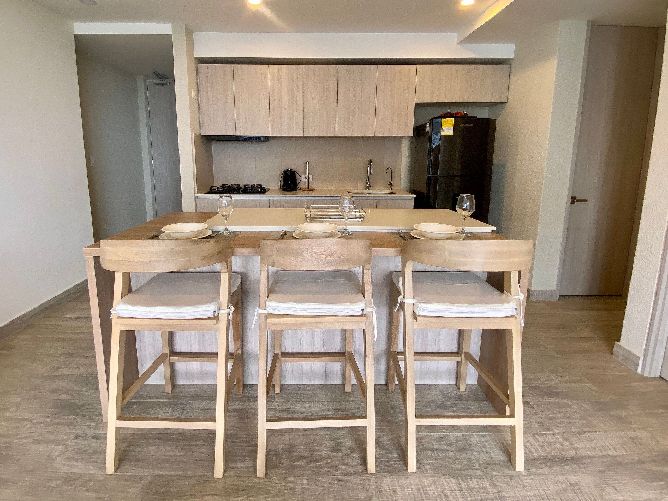Eine moderne Küche mit Holzausstattung, einer Kochinsel und Barhocker.
