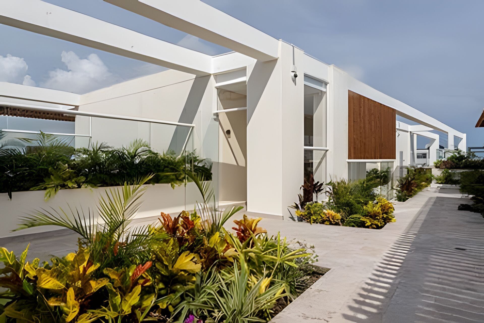 A modern building with a white facade, large windows, and a wooden panel on the side.