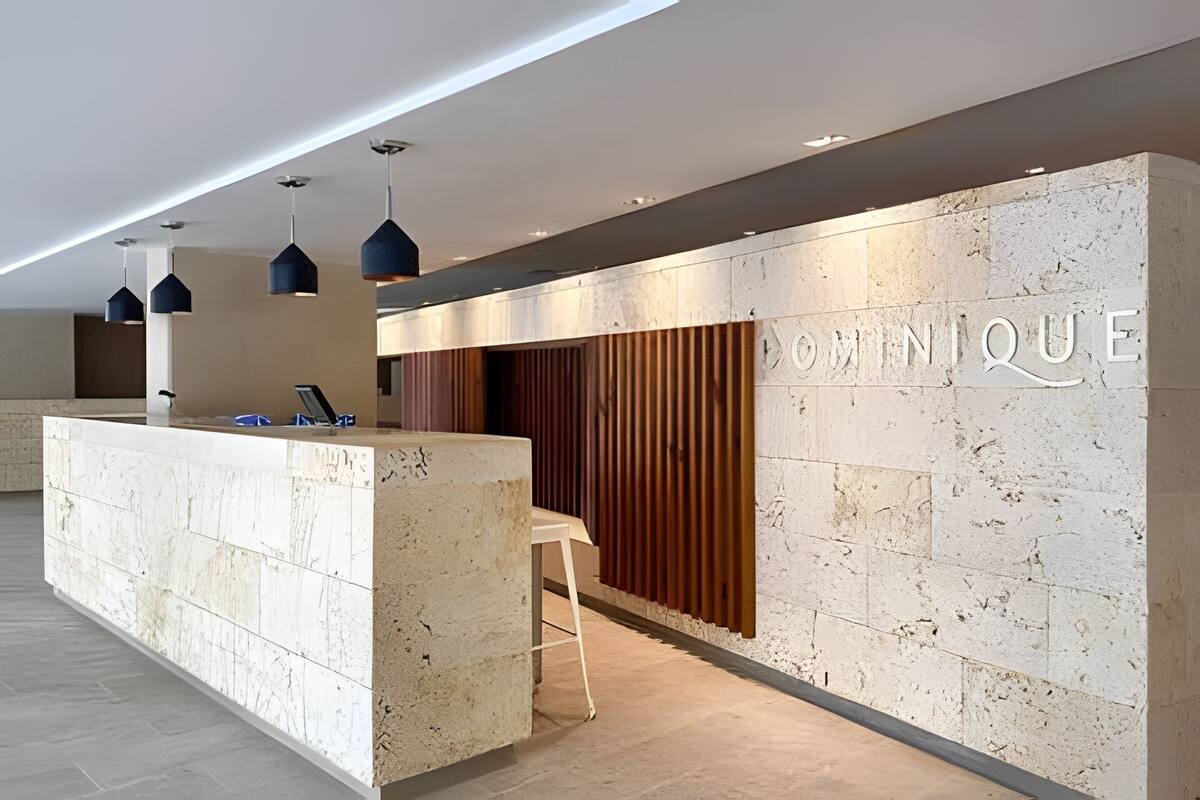 A modern reception area with a marble counter, pendant lighting, and a wooden panel wall with 'MINIQUE' engraved.