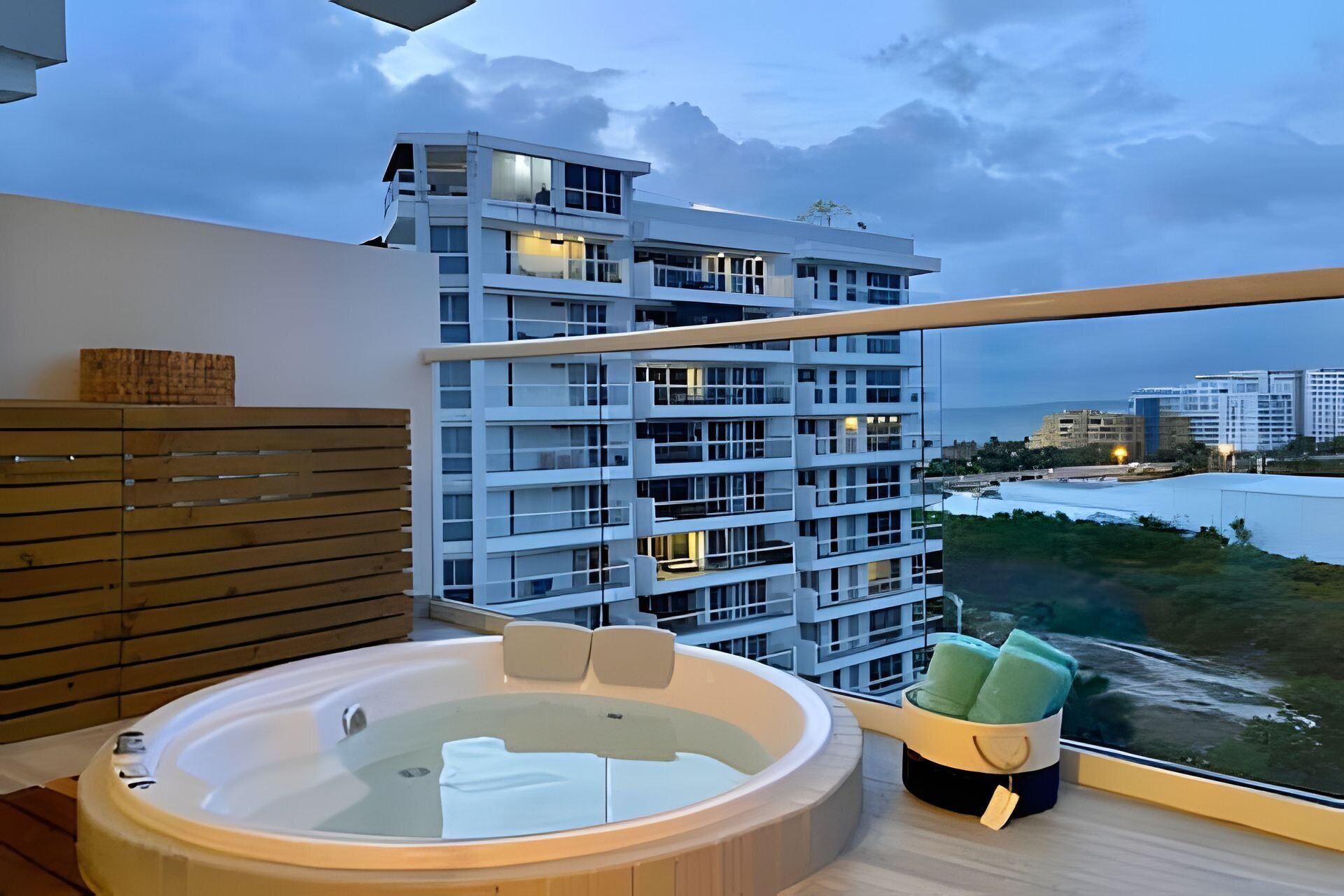 Un baño moderno con jacuzzi, listones de madera y vistas a un edificio alto.
