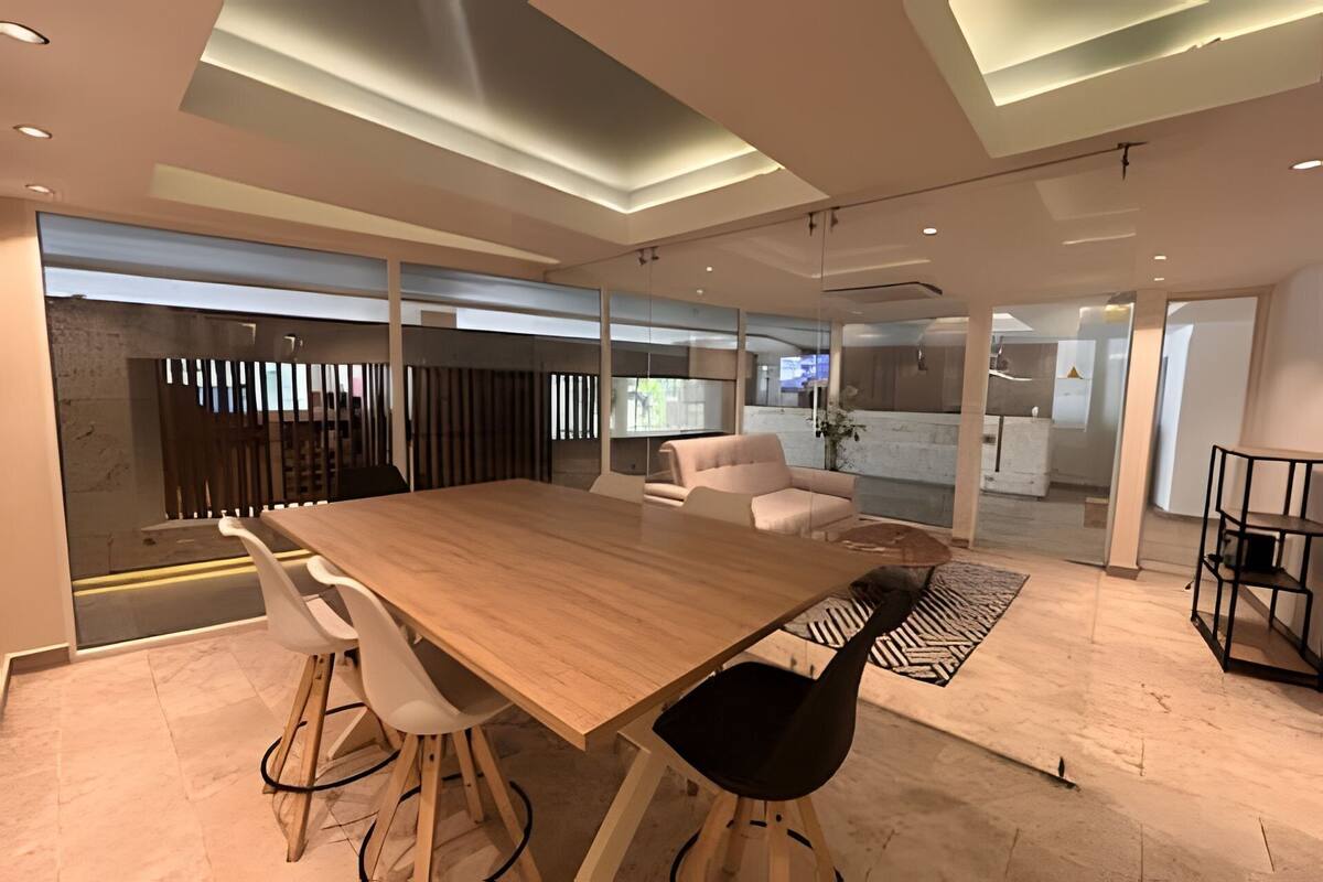 A modern conference room with a wooden table, white chairs, and a glass partition.