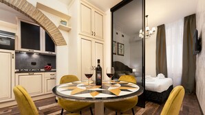 Una cocina moderna con armarios blancos, horno empotrado y comedor con una mesa redonda y sillas amarillas.