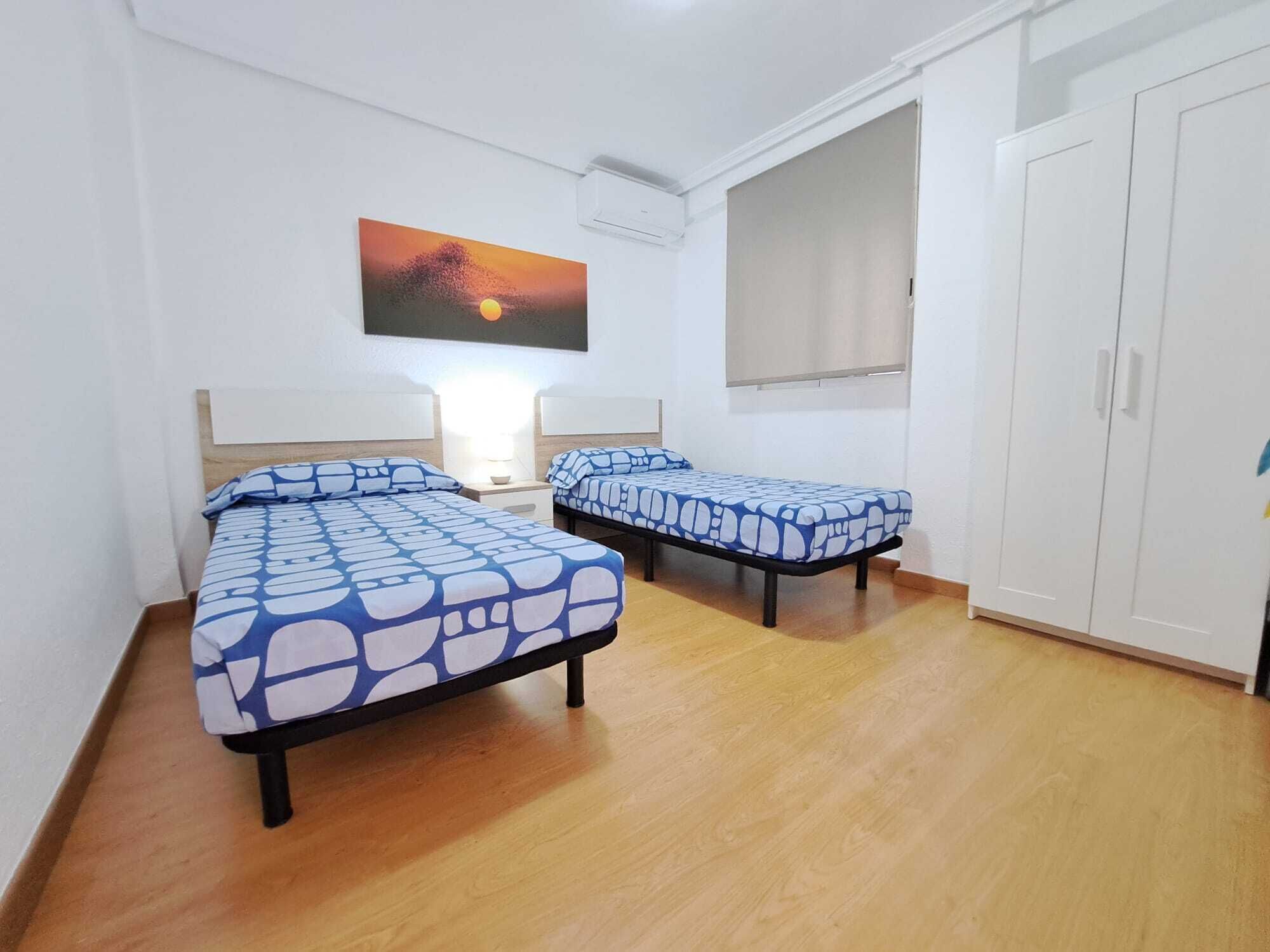 Una habitación con dos camas, un armario y un cuadro en la pared.