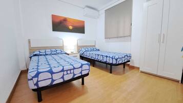 Una habitación con dos camas, un armario y un cuadro en la pared.