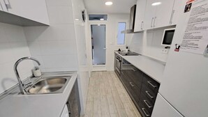Een moderne keuken met witte kasten, roestvrijstalen apparatuur en een houten vloer.