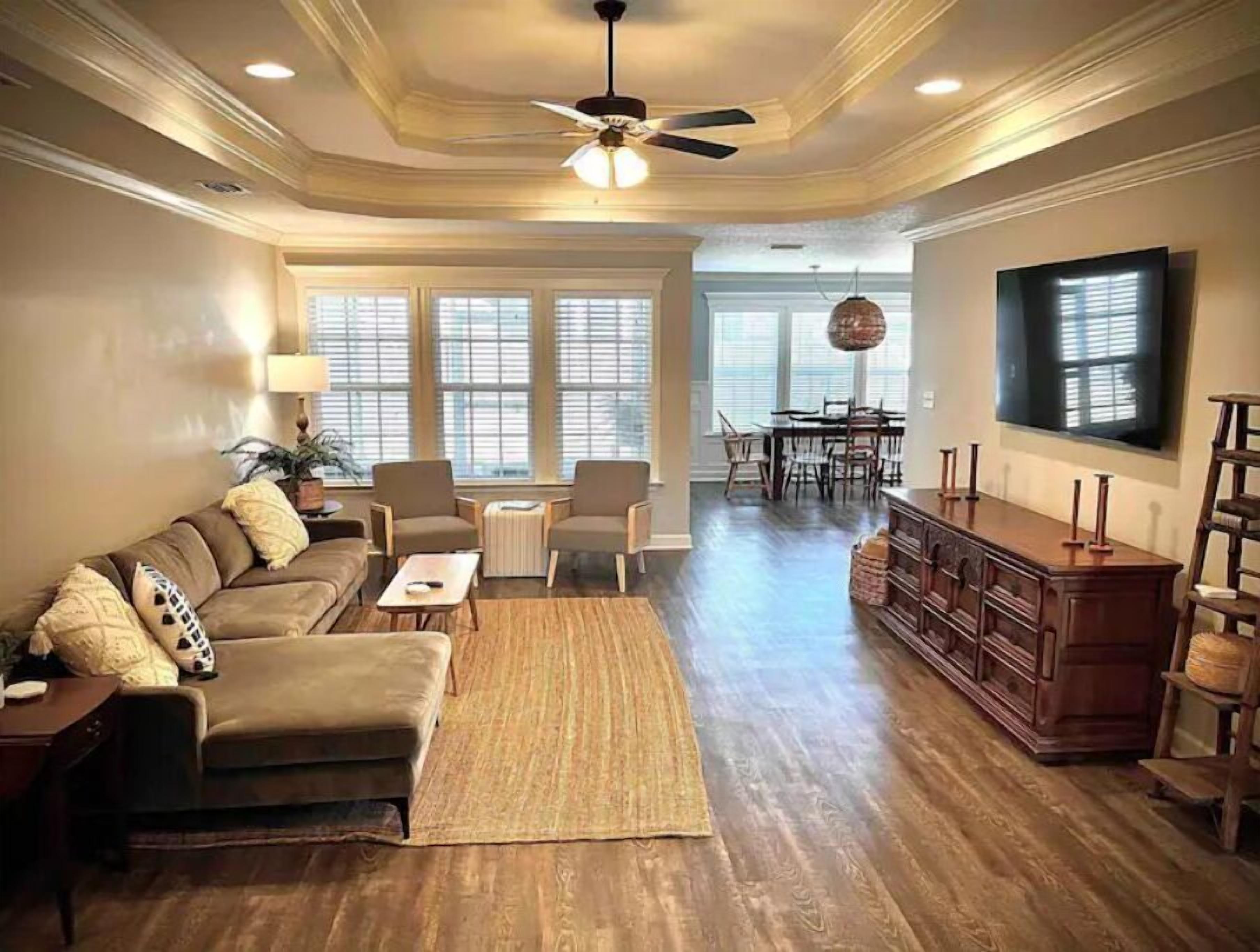 A spacious living room with a sofa, chairs, a coffee table, a wooden cabinet, and a television.
