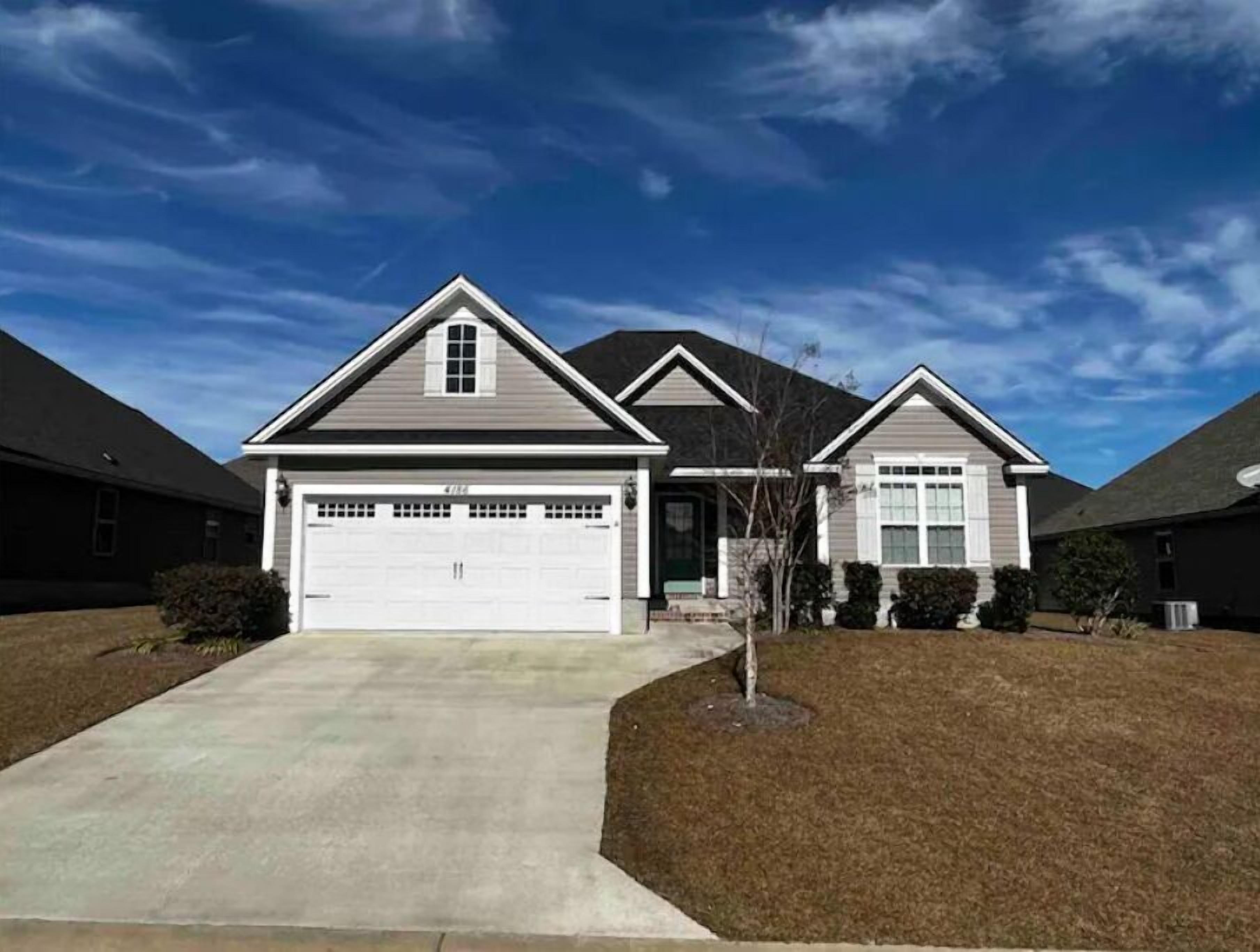 A two-story residential house with a garage, a front yard, and a clear sky.