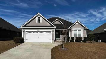 A two-story residential house with a garage, a front yard, and a clear sky.