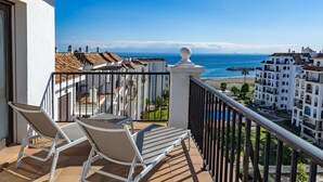 A balcony with two lounge chairs, a view of the sea, and buildings in the background. - Marina Duquesa 2411 Sea View Penthouse (Manilva)
