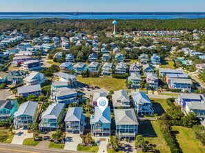 A coastal residential area with multiple two-story houses, a prominent water tower, and a clear view of the ocean.