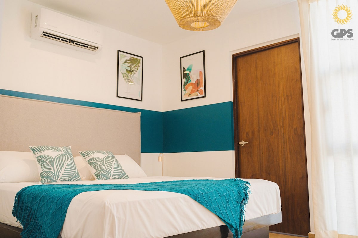 A hotel room with a bed, a wooden door, and two framed pictures on the wall.