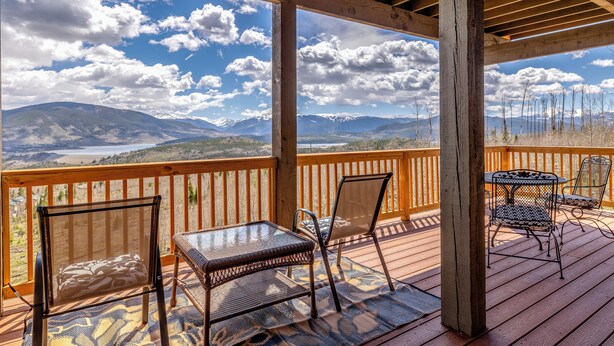 A wooden deck with a table and chairs, overlooking a mountainous landscape. - Newly Updated 5 Bedroom Townhome with Gorgeous Deck Views! (Silverthorne)