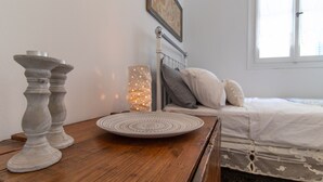 Ein Schlafzimmer mit einem Nachttisch aus Holz, einer dekorativen Platte, einer Wandlampe und einem Bett mit Kissen.
