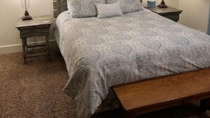 Ein Schlafzimmer mit Bett, zwei Nachttischen, einem Deckenventilator und einer Wanddekoration.